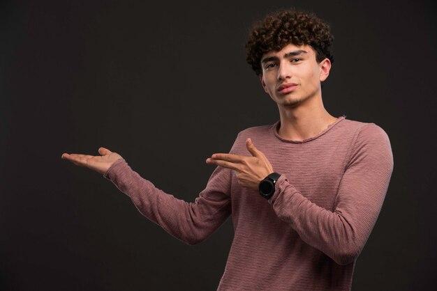 Young boy with curly hairstyle presenting something. 