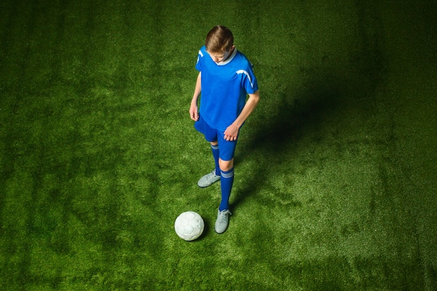 Бесплатное фото Молодой мальчик с футбольным мячом делает летающий удар