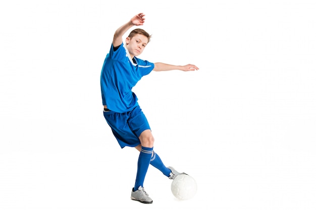 Молодой мальчик с футбольным мячом делает летающий удар