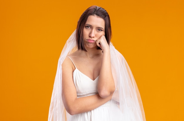 Young bride in beautiful wedding dress tired and bored standing on orange