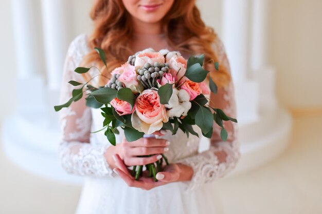 Young bride holds pink wedding bouquet