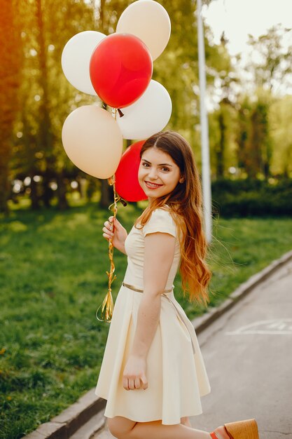 young and bright girls walking in the summer park with balloons