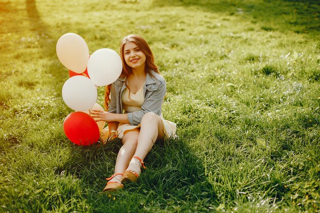 молодые и яркие девушки, идущие в летнем парке с воздушными шарами