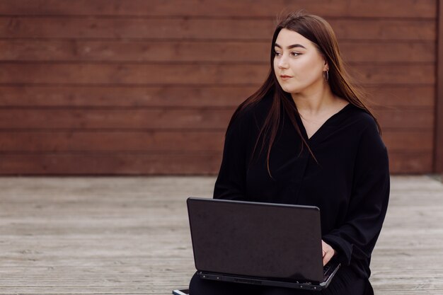 Young brown hair woman with laptop and smart phone computer sitting on wood floor