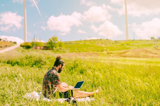 Young brunet male sitting with laptop in rural