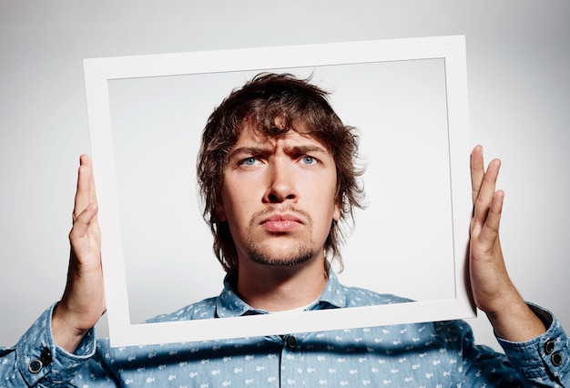 Free photo young brunet man wearing blue shirt and holding frame