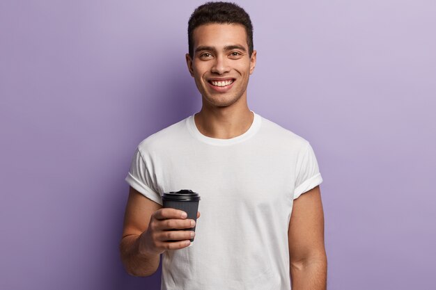 Young brunet man wearing white T-shirt and holding coffee cup