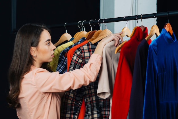 Free photo young brunette choosing clothes in shop