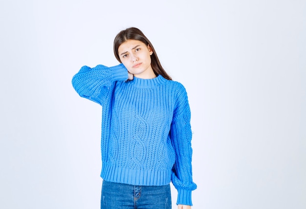 白で疲れを感じている青いセーターの若いブルネットの女の子。