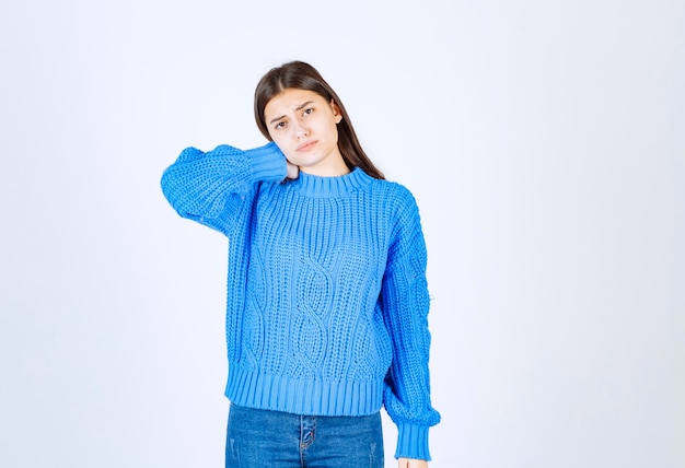 Young brunette girl in blue sweater feeling tired on white.