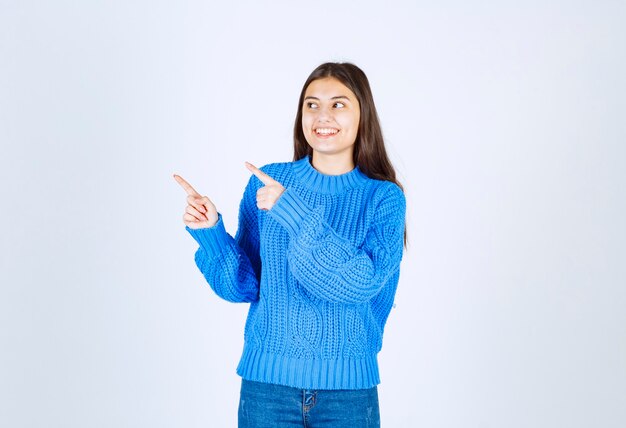 Young brunette girl in blue sweater looking forward on white.