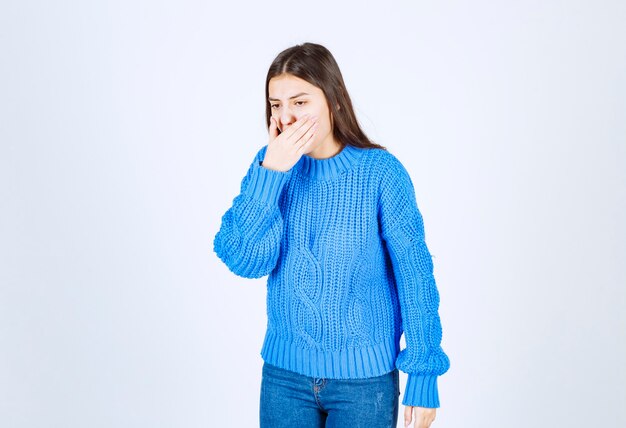 Young brunette girl in blue sweater wants to throw up on white.kk