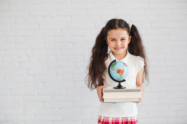 Young brunette girl grinning holding stack of books