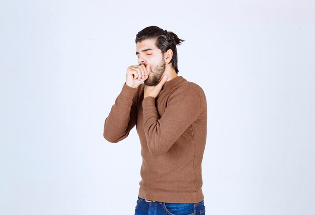 young brunette man coughing and holding throat .