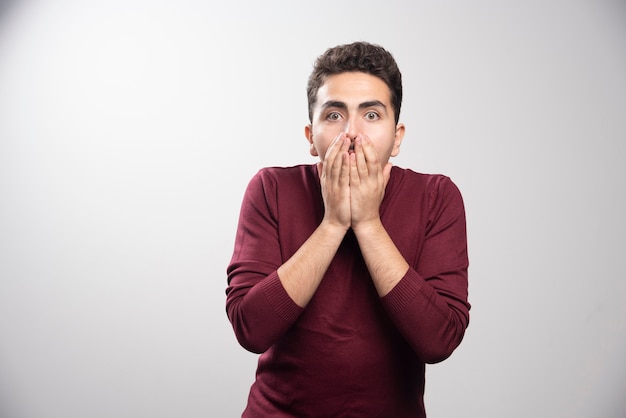 Free photo a young brunette man covering his mouth and posing .