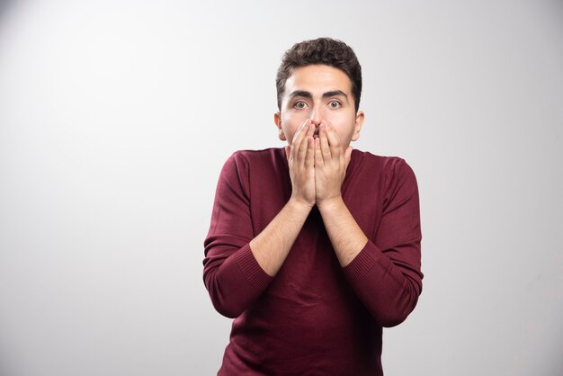 A young brunette man covering his mouth and posing .