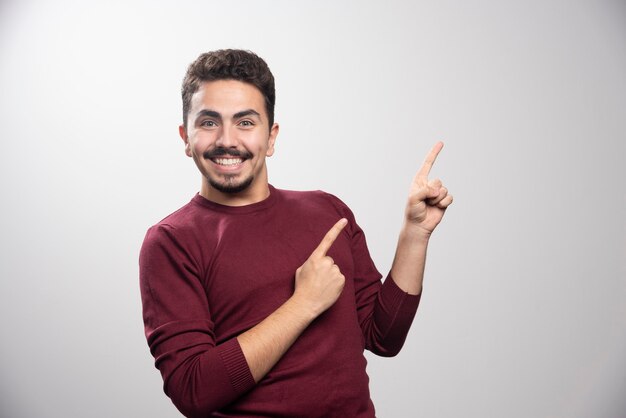 A young brunette man showing fingers up