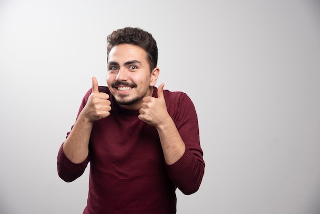 A young brunette man showing thumbs up .