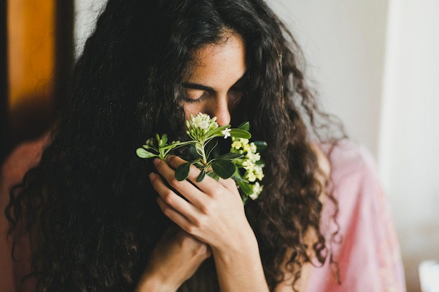 Young brunette smelling flowers