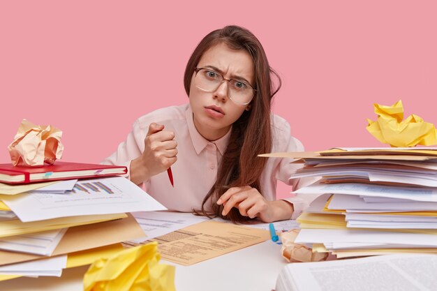 Young brunette student sitting at desk with books