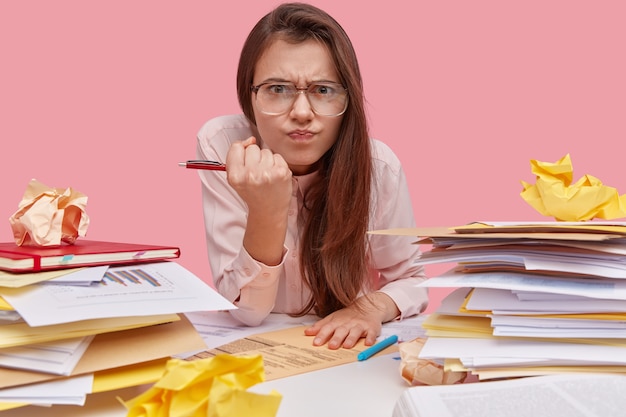 Foto gratuita giovane studentessa bruna seduto alla scrivania con i libri