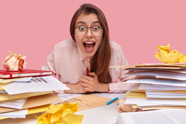 Young brunette student sitting at desk with books