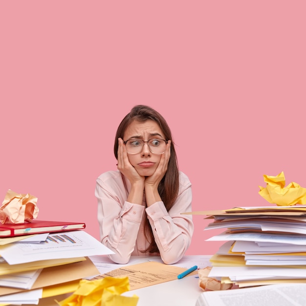 Young brunette student sitting at desk with books