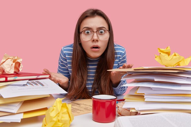 Young brunette student sitting at desk with books