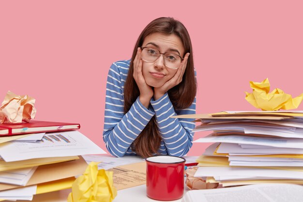 Young brunette student sitting at desk with books