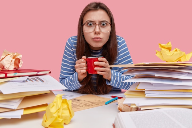 Foto gratuita giovane studentessa bruna seduto alla scrivania con i libri