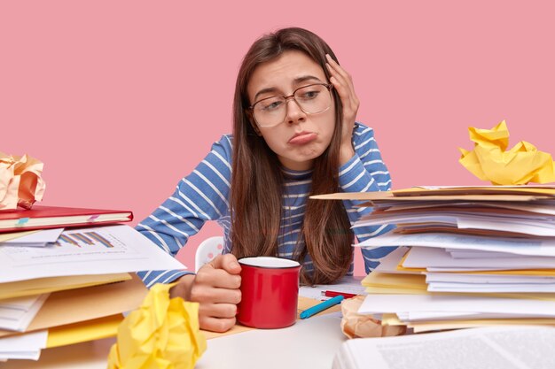 Young brunette student sitting at desk with books