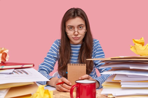 Young brunette student sitting at desk with books