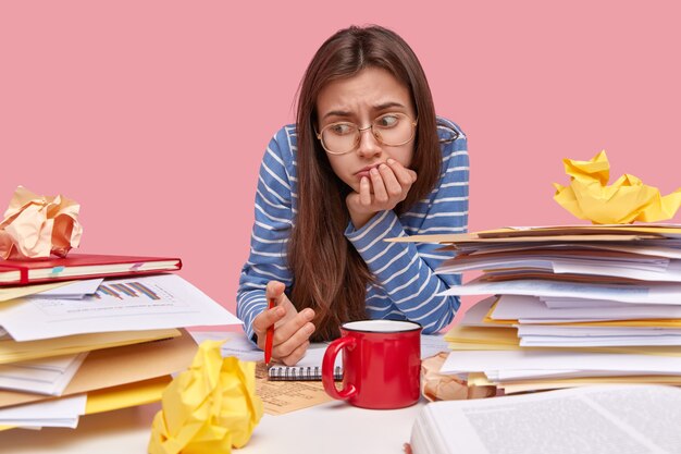 Young brunette student sitting at desk with books