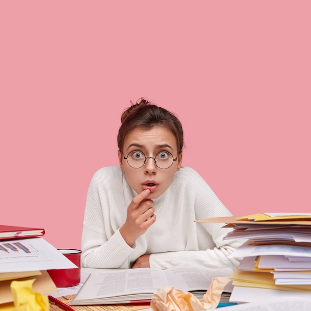 Young brunette student sitting at desk with books