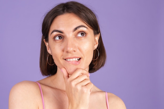 Young brunette in top isolated on purple wall