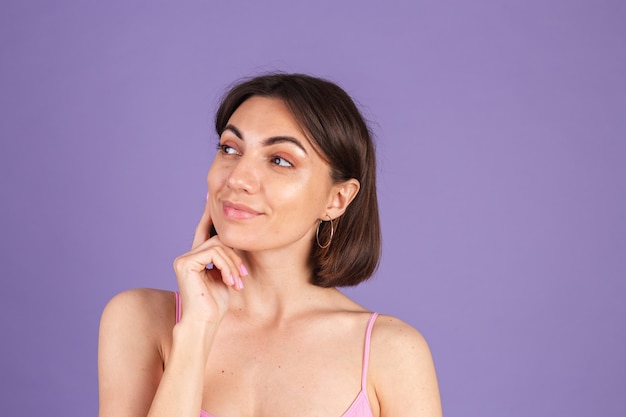 Young brunette in top isolated on purple wall