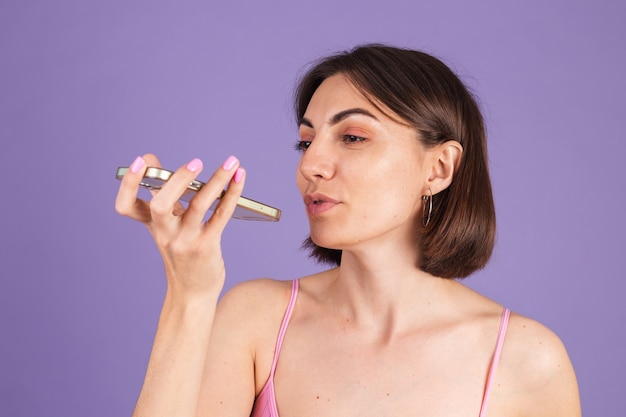 Young brunette in top isolated on purple wall