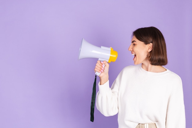 Young brunette in white casual sweater isolated on purple wall