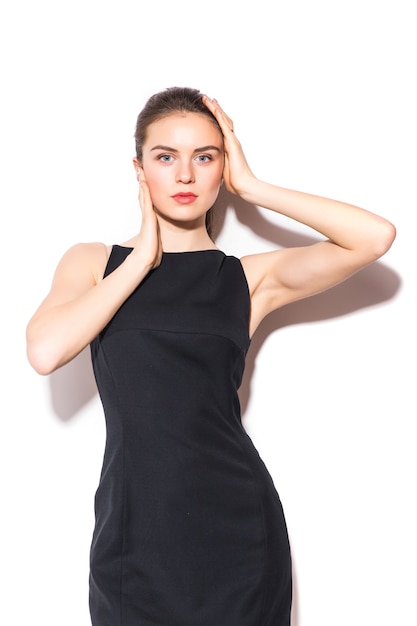 Young brunette woman in black dress posing on white background