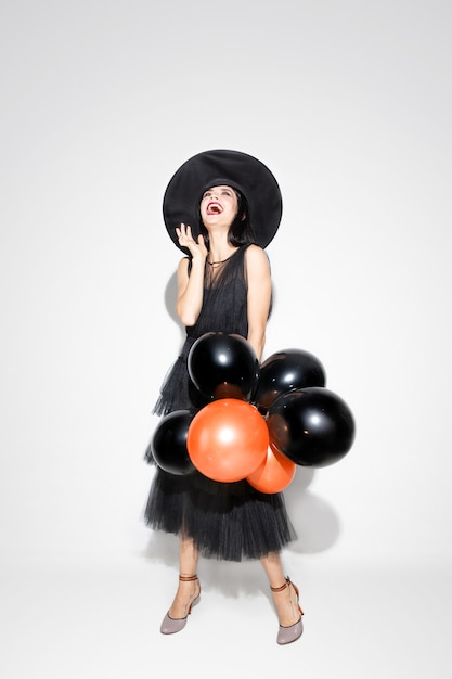 Free photo young brunette woman in black hat and costume on white