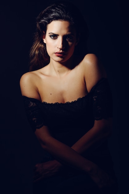 Young brunette woman in black lingerie in chiaroscuro lighting. 