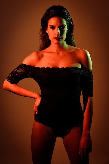 Young brunette woman in black lingerie with red and green lighting. 