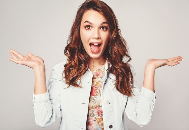 Young brunette woman in casual summer clothes displaying something on both flat hands