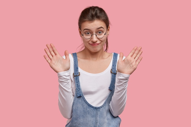 Young brunette woman in denim overalls