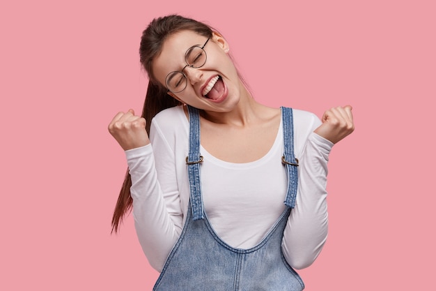 Foto gratuita giovane donna castana in salopette di jeans