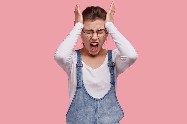 Foto gratuita giovane donna castana in salopette di jeans