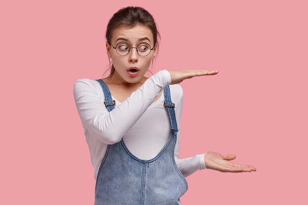 Young brunette woman in denim overalls