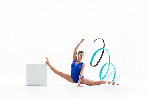 young brunette woman gymnast training calilisthenics exercise with blue ribbon