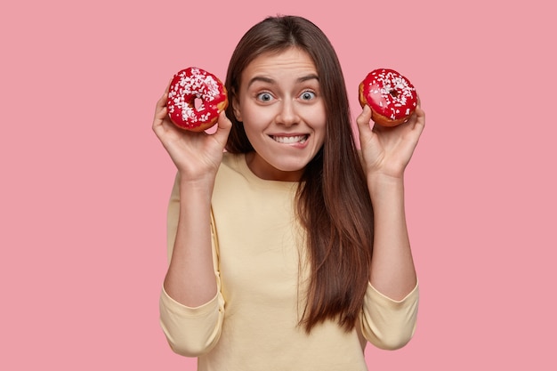 Free photo young brunette woman holding tasty donuts