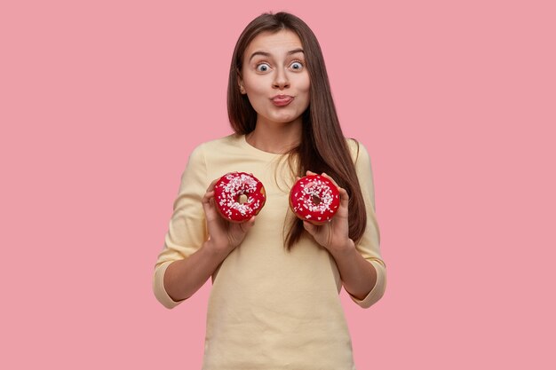 Young brunette woman holding tasty donuts